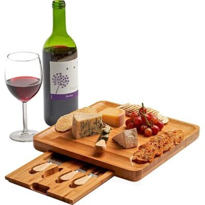 Cheese items are placed on the cheese cutting board and cheese knives are in separate drawer within the board with glass of red wine and red wine bottle