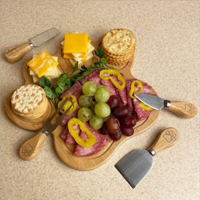 Dog paw shape characuterie board with four types of wooden handle steel knives and cheese board is decorated with fruits cheese layer crackers meats Dog paw shape characuterie board with four types of wooden handle steel knives and cheese board is decorated with fruits cheese layer crackers meats