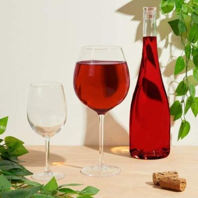 Large red wine glass with leaves the background