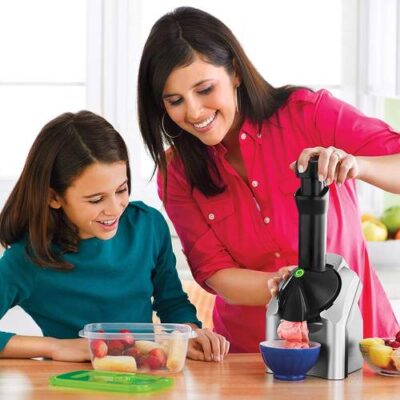 Mom and daughter making fruit desert with ice cream machine