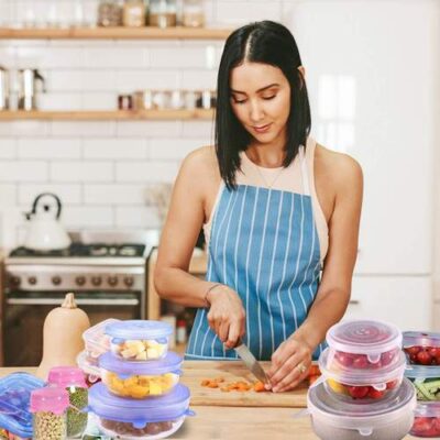 Woman cuts vegetables in the cutting board and stored in the boxes and closed with silicone stretch lids