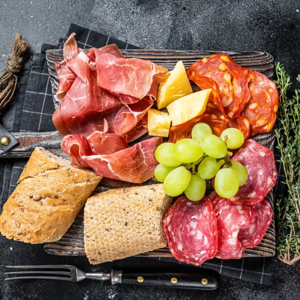 cold meat plate charcuterie traditional spanish tapas wooden board with bread grape black background top view