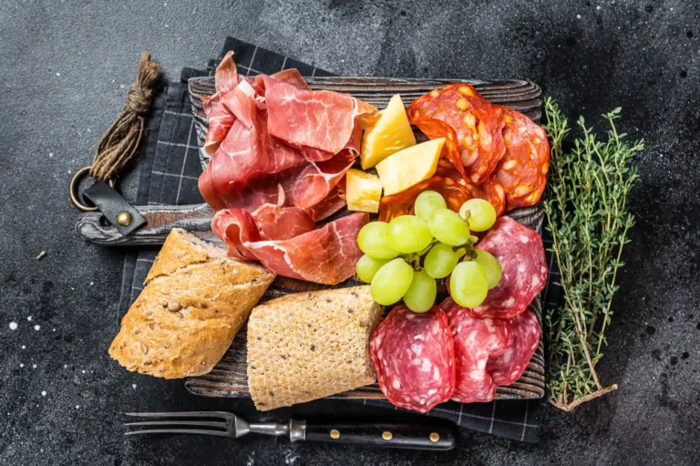 cold meat plate charcuterie traditional spanish tapas wooden board with bread grape black background top view