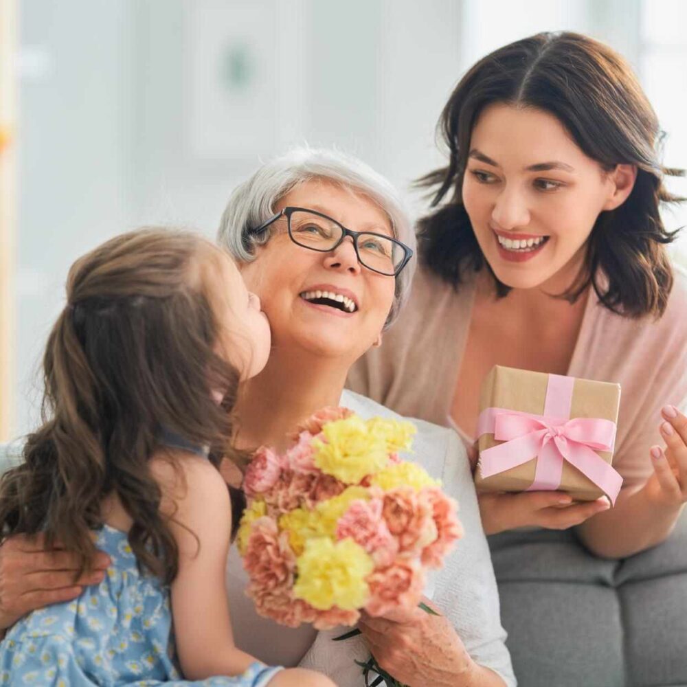 hapy mother daughter and grand daughter laughing with gifts flowers and balloon