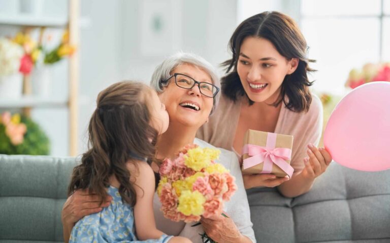 hapy mother daughter and grand daughter laughing with gifts flowers and balloon