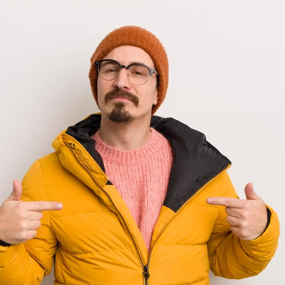 young handsome man with coat against white wall