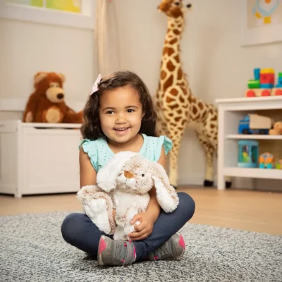 A kid sitting on the rug mat cuddling the bunny in her playing room