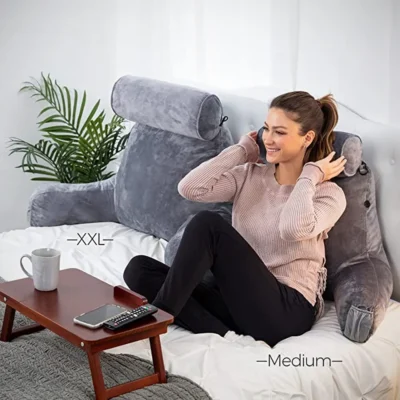 A woman sitting on the bed using XXL husband pillow with her coffee mobile kept on the tiny table