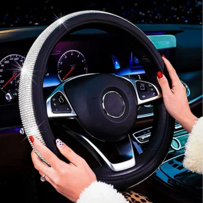 A Girl has stylish nails driving the car with the steering covered with diamond stone